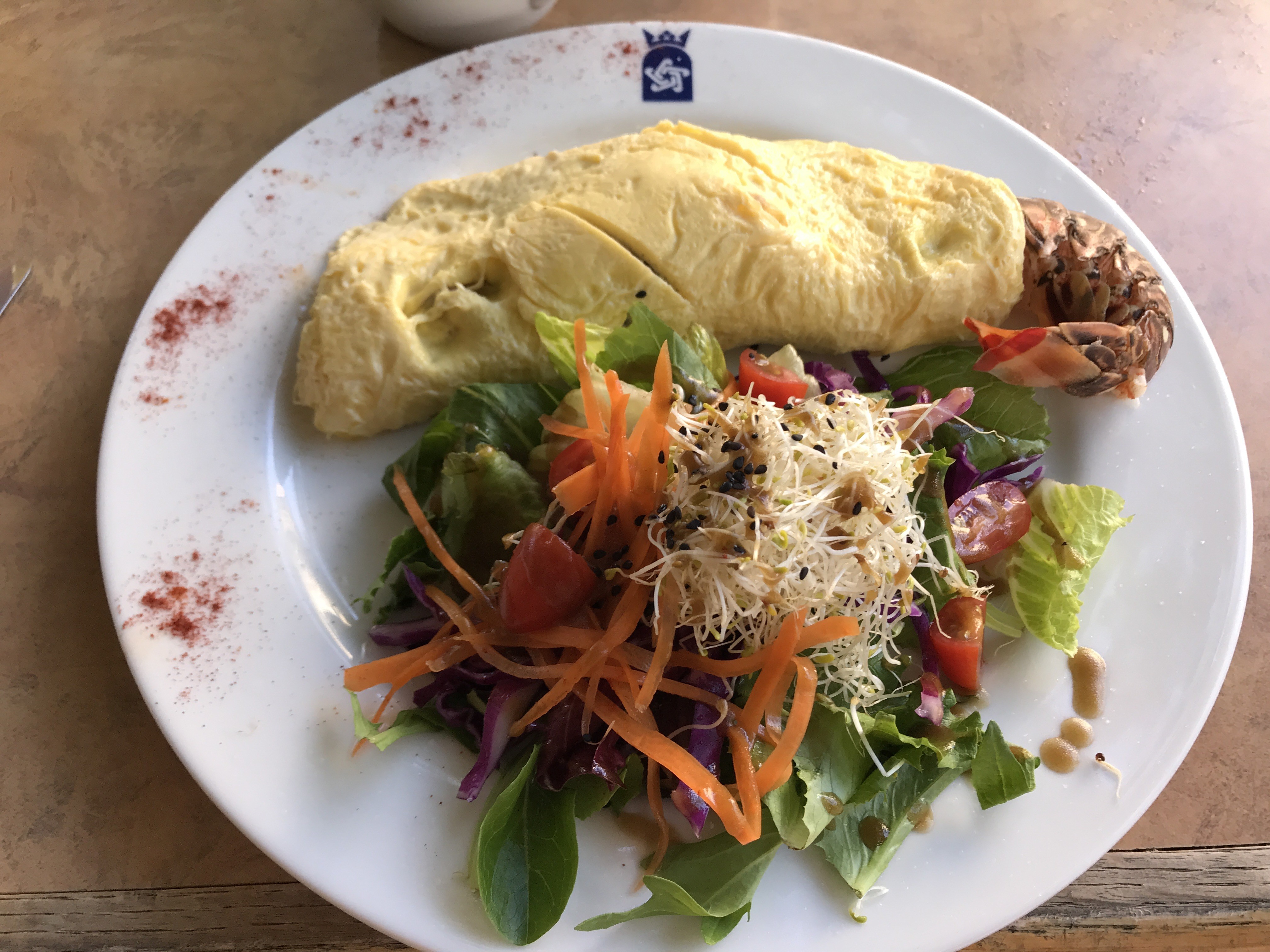 A pale folded omelet served with lobster tails and a fresh salad
